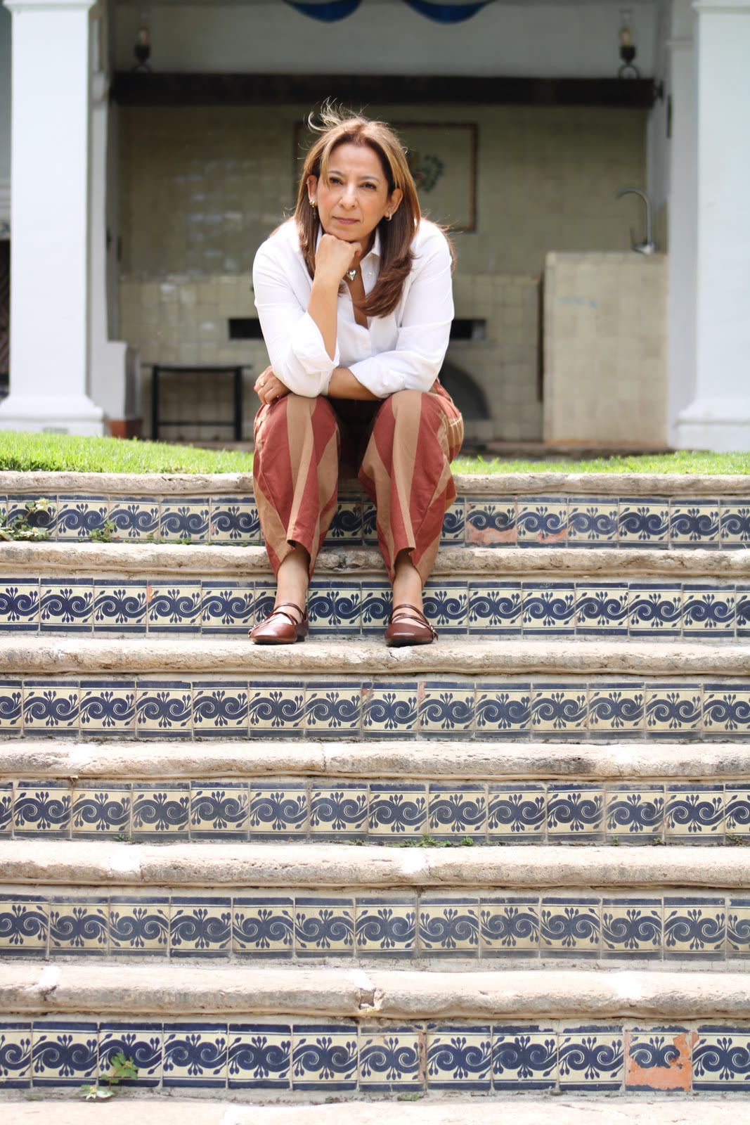 Xóchitl mira al frente sentada con determinación sobre escalones de azulejo.